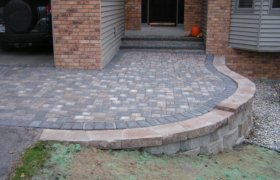 Elegant outdoor living space created using brick patio pavers and landscap block, designed and installed by Exterior Designs of Alexandria